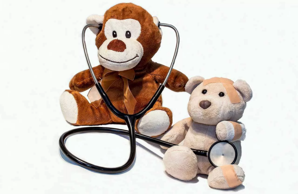 two teddy bears with a stethoscope used to draw attention to "how often do you take a cat to the vet"
