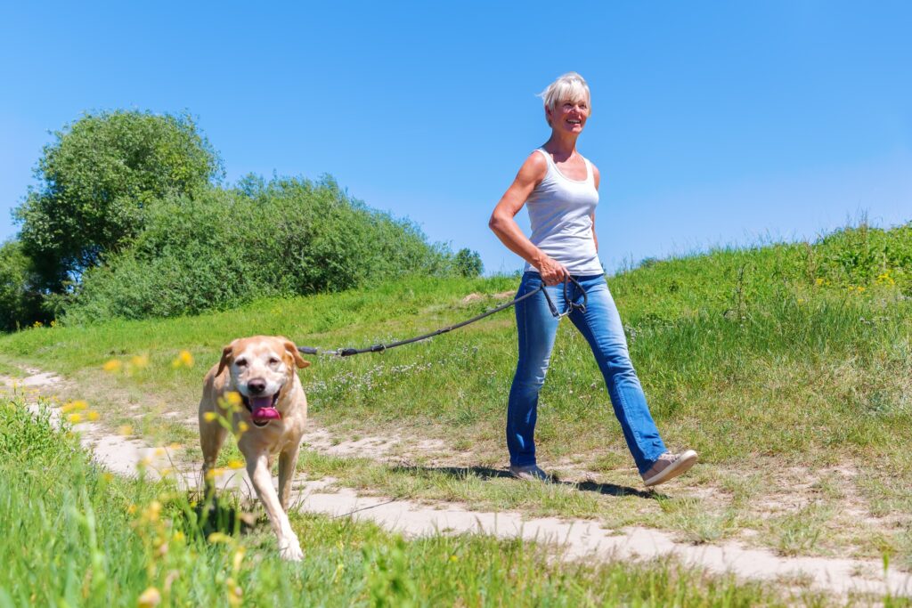 fit senior woman walking a dog on a leash