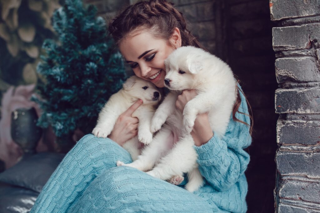pretty woman holding two white large breed puppies